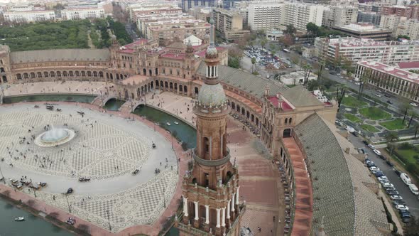 Orbiting over Plaza de España tower revealing majestic Square full of tourists, Seville