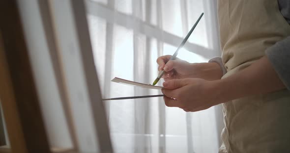 Professional Artist Woman Is Working in Studio Painting Picture on Canvas Mixing Dyes on Palette alt