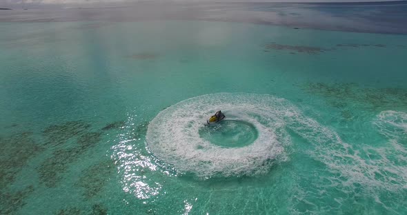 Aerial view of man racing water scooter on turquoise crystal clear water of the ocean in Maldives