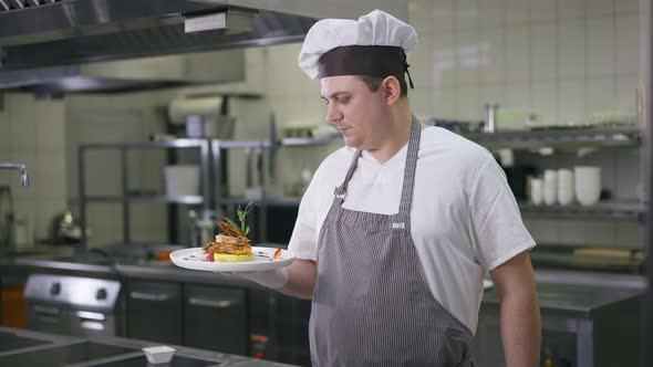 Satisfied Caucasian Chef Standing in Commercial Kitchen with Cooked Prawn on Plate Turning Looking alt