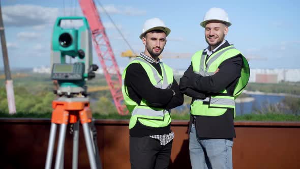 Portrait of Two Confident Young Engineers with Crossed Hands Looking at Camera Smiling Standing on alt