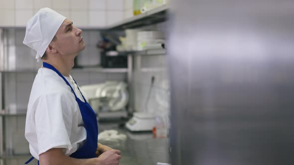 Side View Portrait Concentrated Caucasian Cook Choosing Additives in Commercial Kitchen Indoors alt