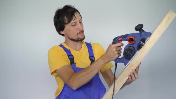 A Man Professional Tile Installer a Wooden Plank and an Electric Planer in His Hands alt