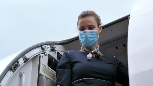 Flight Attendant with Coronavirus Protection Mask Closes Aircraft Door alt