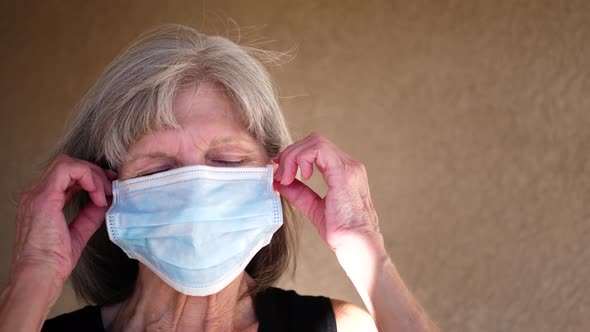 An aging woman smiling and taking off her hospital medical mask after being cured of her cancer dise alt