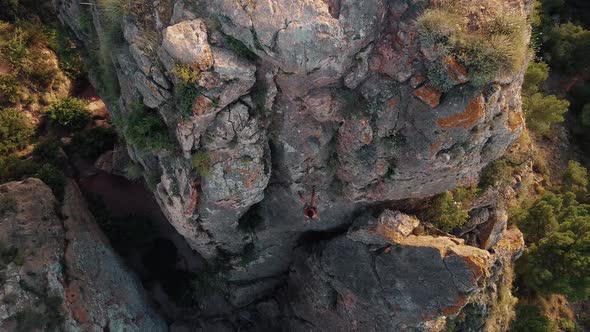 Climbing sportswoman rappelling in the mountain. Drone view of climber young fit girl descending. alt