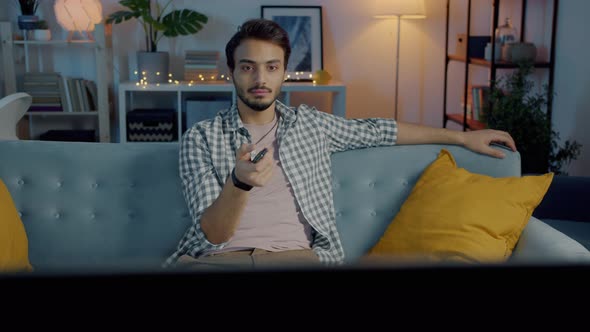 Male Student Watching TV at Night Using Remote Control Enjoying Leisure Time Alone at Home alt