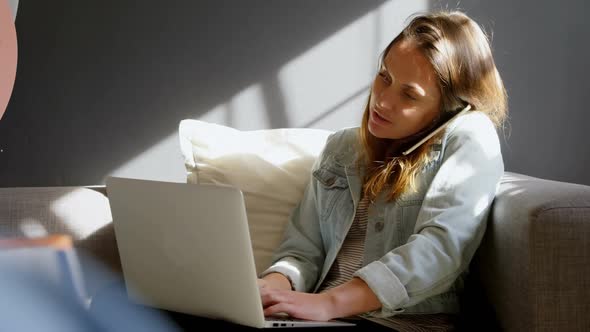 Female jewelry designer talking on mobile phone while using laptop 4k alt