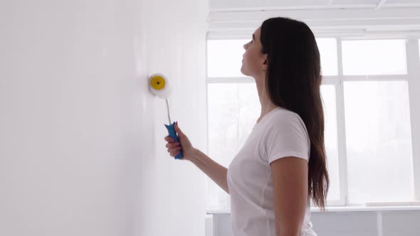Young Lady Making Home Renovation Painting Wall with Painter and White Dye alt