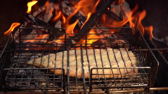 Mouthwatering Mackerel Fish is Roasting on the Grill Grid in Flames alt