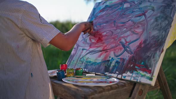 Little Male Artist Picks Up Paint with His Finger and Draws a Picture on the Canvas While Relaxing