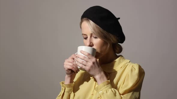 Stylish woman with cup of coffee on grey background