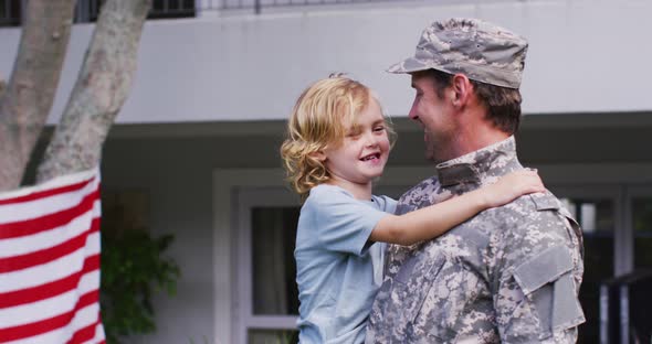 Caucasian military dad in uniform picking up his son in the garden alt