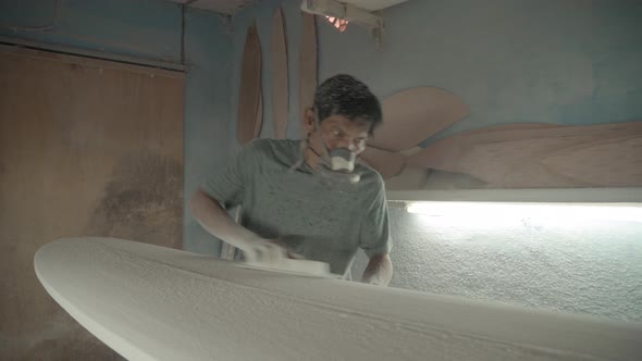 Artisan Sanding Surfboard Using Sandpaper alt