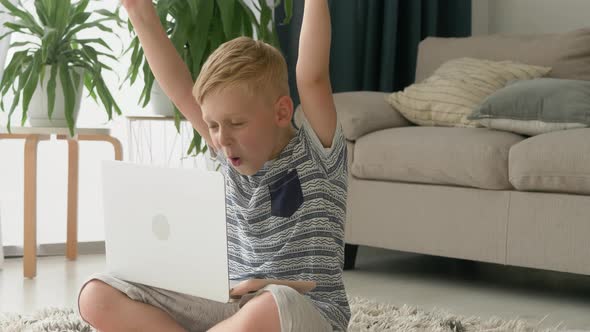 little blonde boy using computer laptop screaming proud and celebrating victory