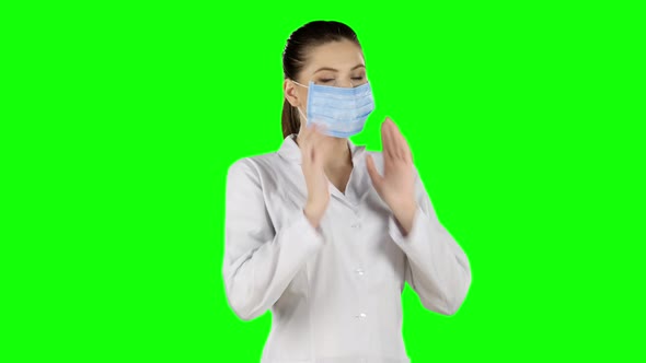 Young Attractive Woman Putting on Health Mask. Green Screen alt