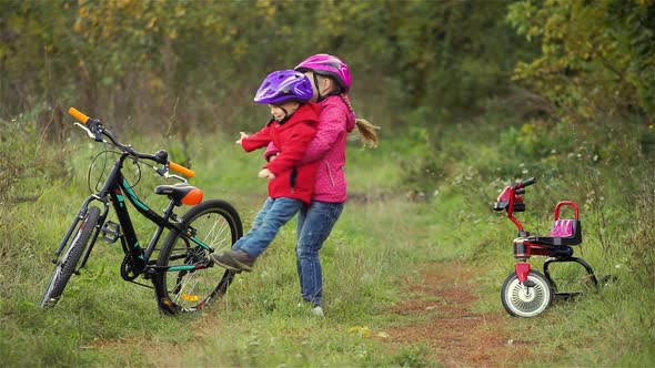 Little boy and girl dancing near bicycles outdoors, sister circling brother, autumn comes