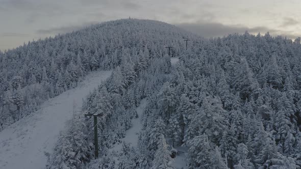 Abandonded ski lift at the peak of a snow covered mountain SLOW AERIAL SLIDE alt