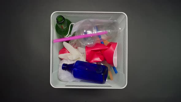 Throwing Plastic Garbage in the Metal Trash Can on Black Background Top View alt