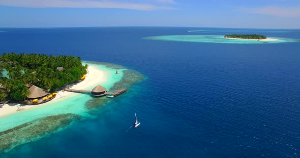 Aerial drone view of a man and woman sailing on a boat to a tropical island. alt