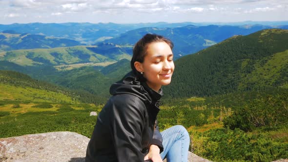 A Young Woman Traveler Has Reached the Top of the Mountain and Enjoys a Beautiful View of the Forest