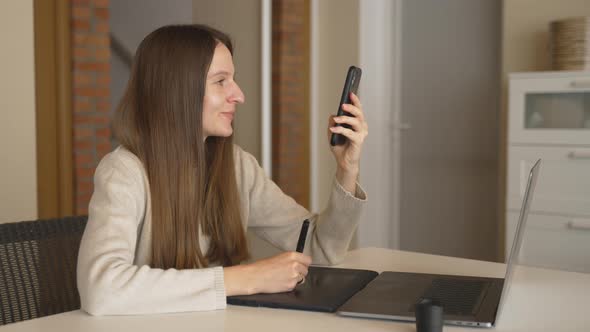 Slow Motion of Brunette Designer Surfing on Phone When Drawing on Tablet at Home