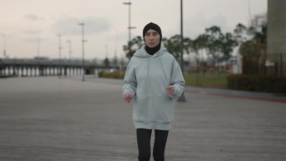 Muslim Female Runner in Hijab Exercising on City Street alt