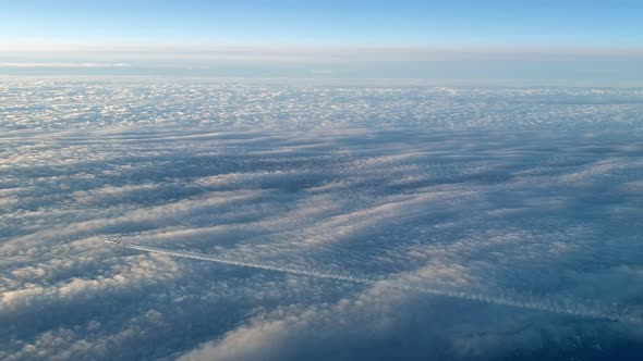Incredible view from the cockpit of an airplane flying high above the clouds leaving a long white co alt