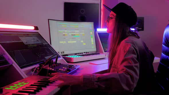 Woman in Designer Glasses Cap and Headphones Working in the Recording Studio with Computer and Mixer