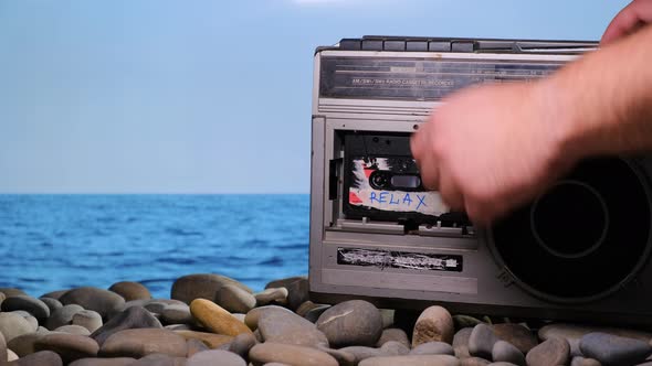 Vacationer Put on Stone Beach Old Vintage Retro Radio Tape Recorder and Puts on Audio Cassette with alt