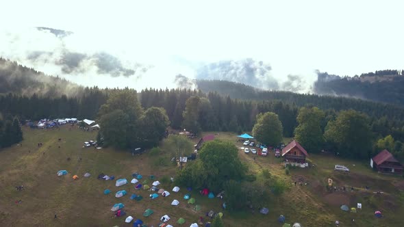 Tilting Aerial Drone Shot Revealing a Romanian Festival Campground with a Gorgeous Mountain Range as alt