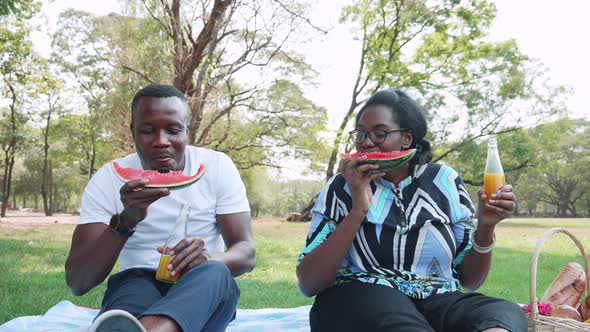 Happy African American Couple eating watermelon and enjoy during picnic together in park