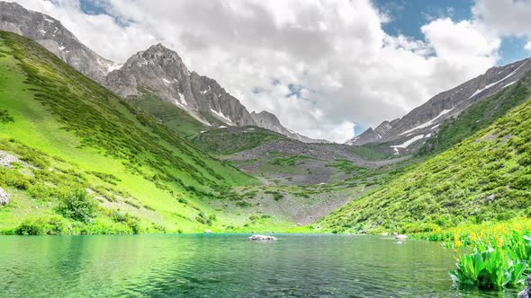 Fast moving clouds over a turquoise alpine lake alt