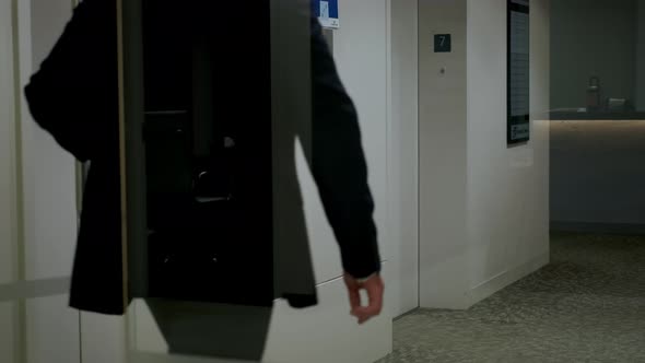 Man Presses Elevator Button to Move Up alt