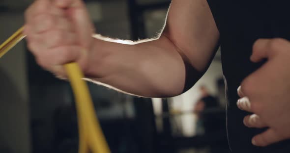 Closeup of Man in Glasses Pulling Loop with Hand at Simulator in a Dark Gym alt
