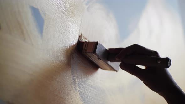 Closeup of the Artist's Hands Holds Wide Brush and Slowly Paint on Canvas Brown Gold Oil alt