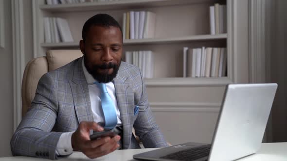 African-American Bearded Man in a Gray Suit, White Shirt. The Businessman Is on the Desktop at a alt