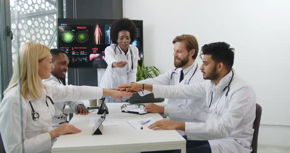 Diverse Team of Doctors which Stacking Hands Together Before Starting the meeting alt