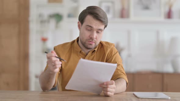 Young Man Reading Documents in Office alt