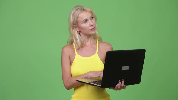 Young Happy Beautiful Blonde Woman Thinking While Using Laptop