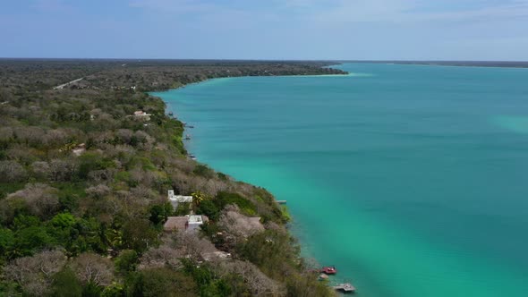 wide aerial coastline of turquoise blue Bacalar Lagoon coastline on sunny day in Mexico alt