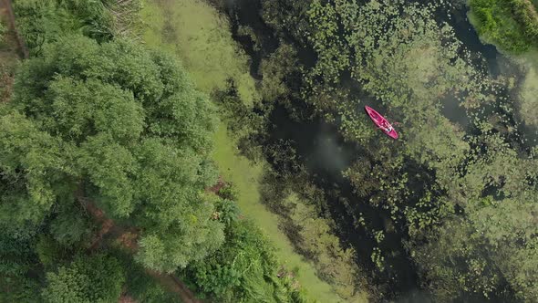 Adventure Activity. Water sports. Red boat or kayak floating on green river top view alt