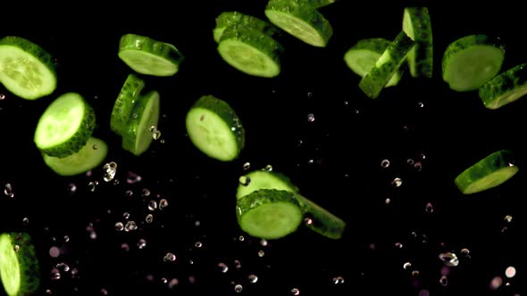 Super Slow Motion Round Pieces of Cucumber Rise with Drops of Water alt