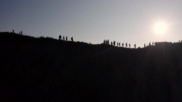 Silhouetted People at the summit of Mout Batur volcano in Bali Indonesia walk along the crater ridge alt