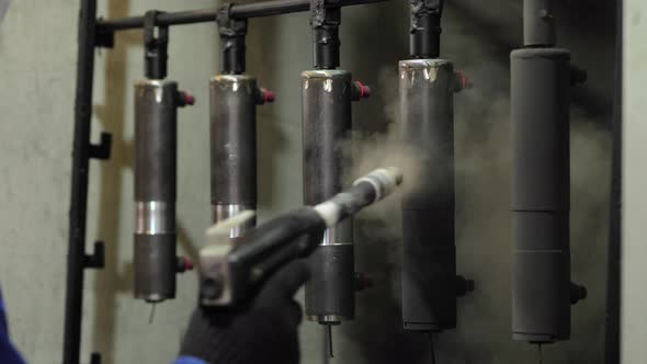 Worker sprays paint on a metal part