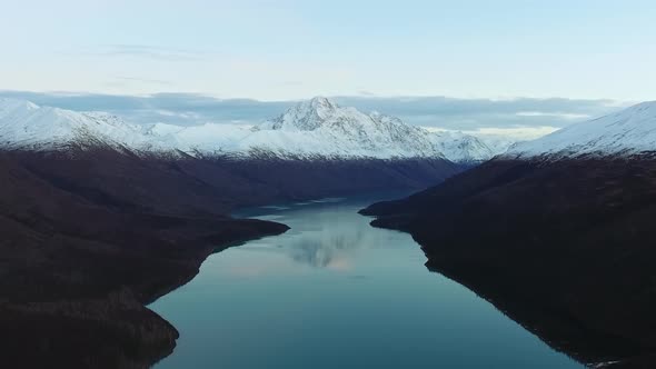 Aerial footage of a lake with a reflection of the mountains and peaks in Eklutna Lake, Alaska, USA alt