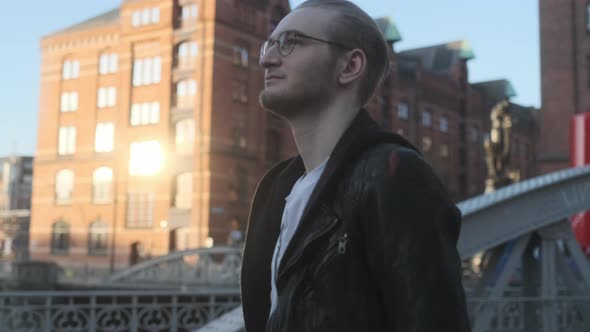 Young European Man with Glasses and Beard walking through City at Golden Hour (Speicherstadt Hamburg alt