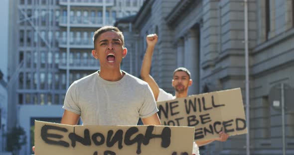 Two mixed race men on a protest march holding placards raising hands and shouting alt