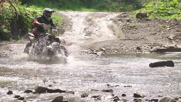 Enduro Motorcyclist Rides on a Shallow River