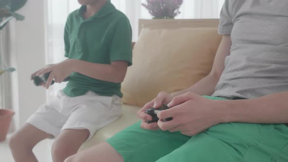 Closeup hand of family with father and son playing video game with joystick on sofa with fun.